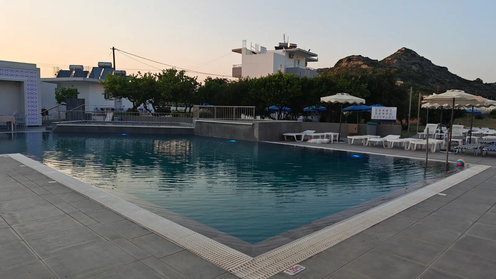 Basen hotelowy na Rodos z leżakami, parasolami i niską zabudową hotelową