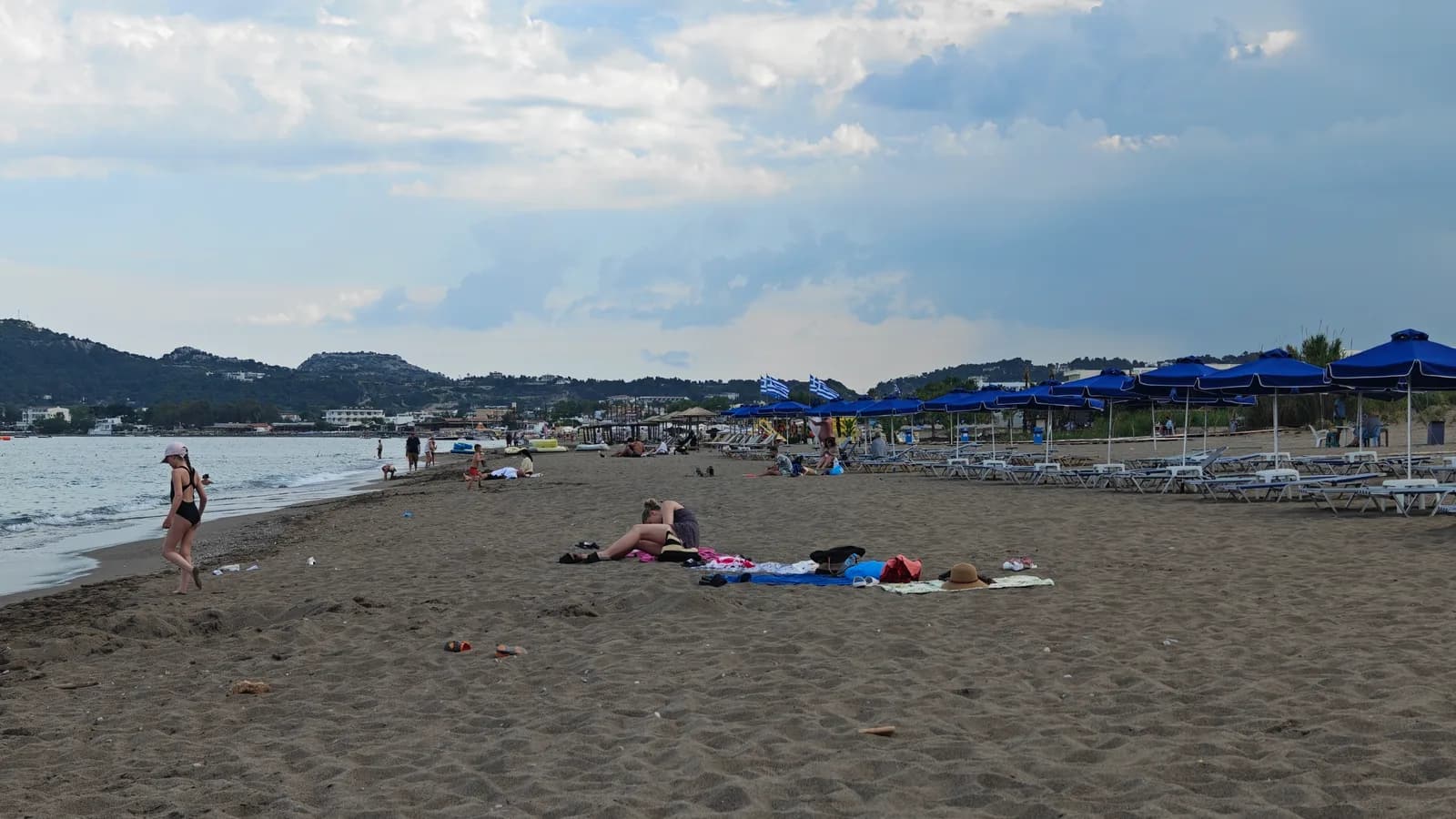 Plaża Faliraki na Rodos z leżakami, parasolami i rodzinami wypoczywającymi przy brzegu