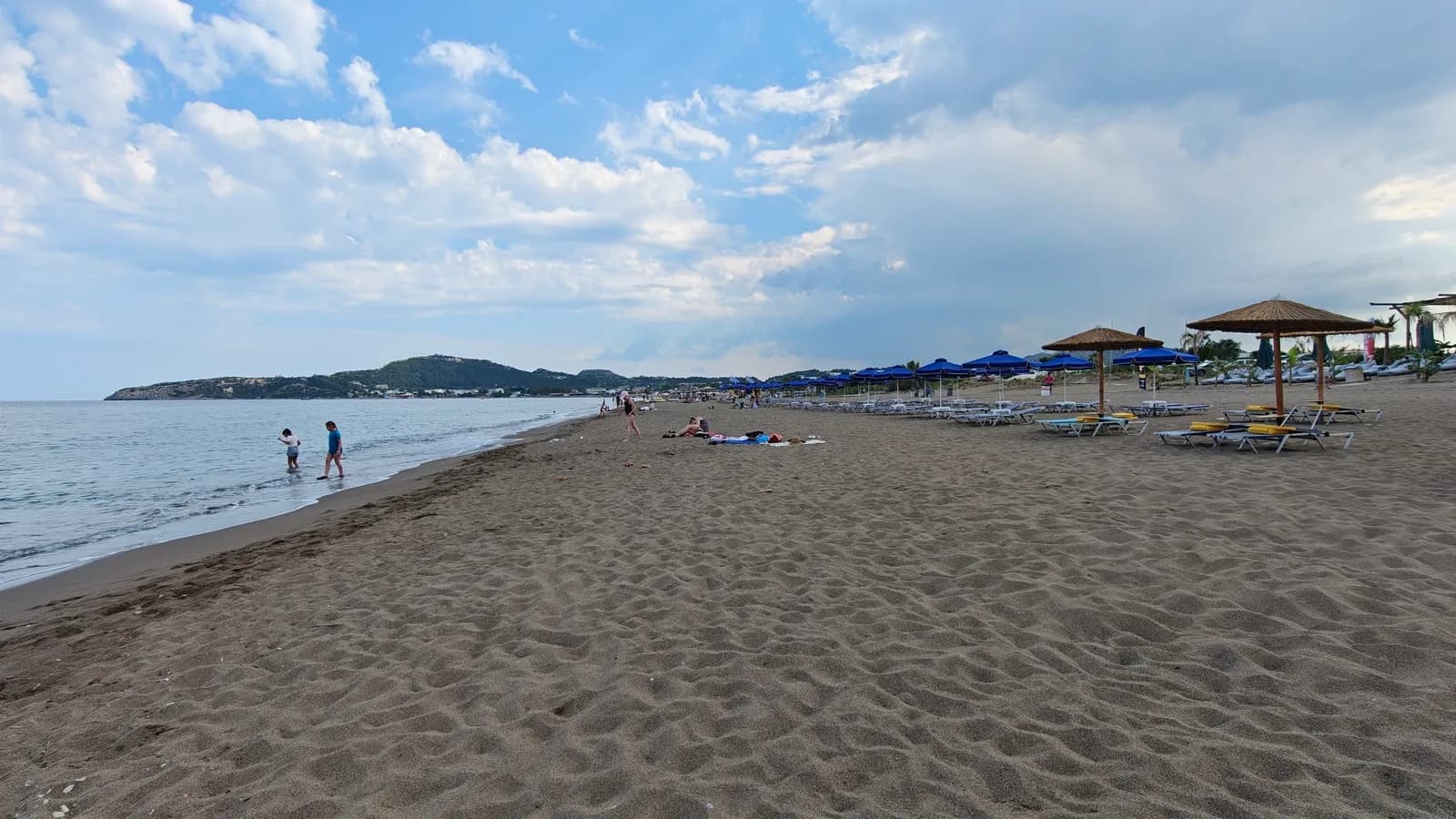 Piaszczysta plaża Faliraki na Rodos z łagodnym wejściem do morza i parasolami