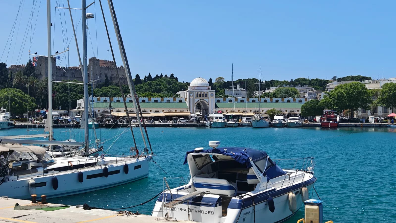 Port Mandraki w mieście Rodos z łodziami, Pałacem Wielkich Mistrzów i zabudową portową