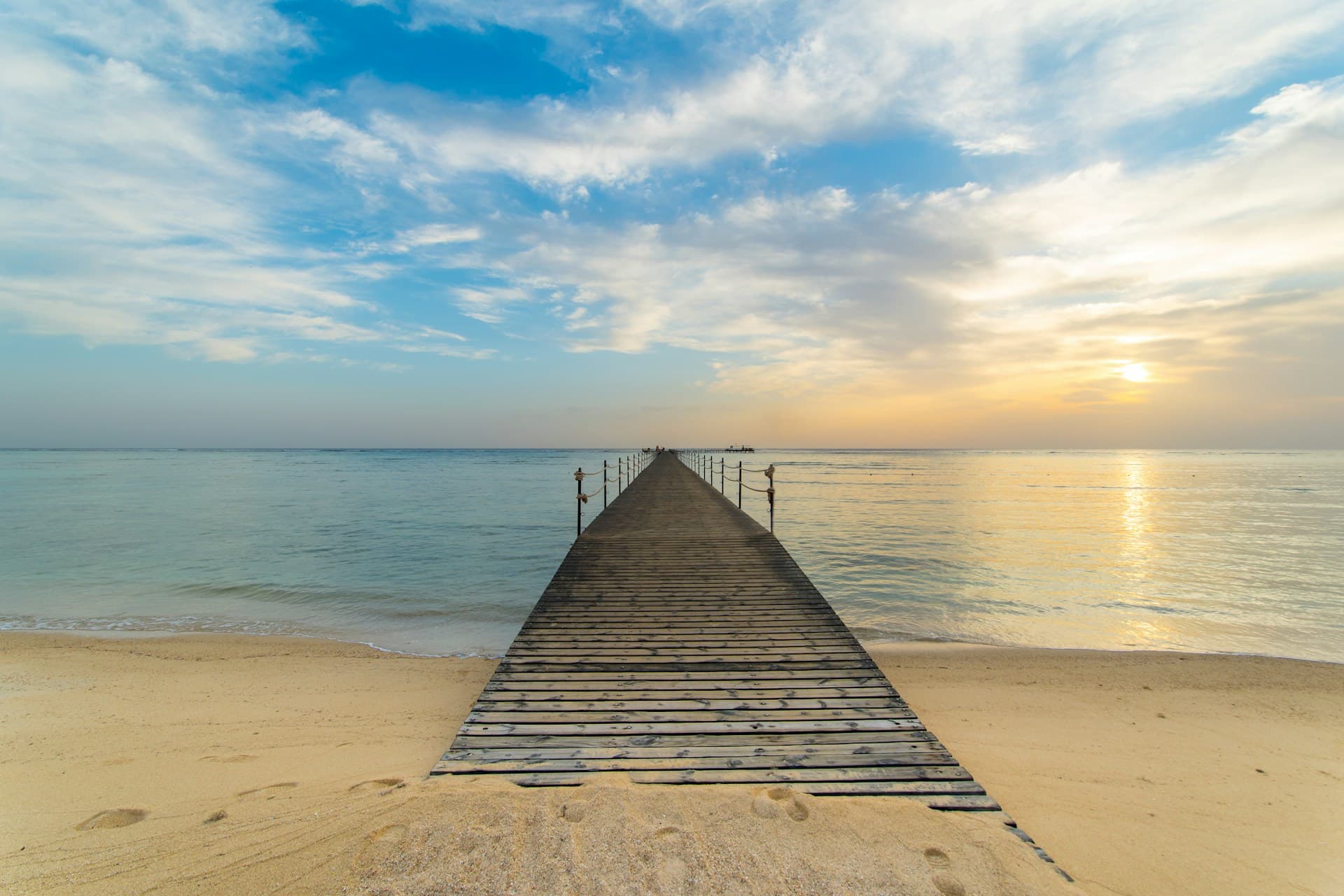 Drewniany pomost nad Morzem Czerwonym przy piaszczystej plaży w rejonie Marsa Alam